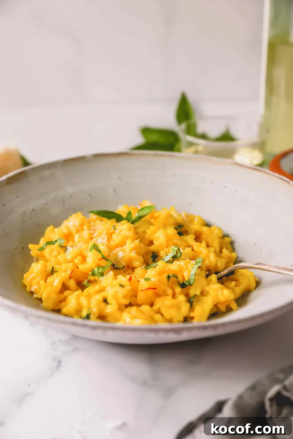 Side view of a bowl of saffron risotto with a spoon sticking out.