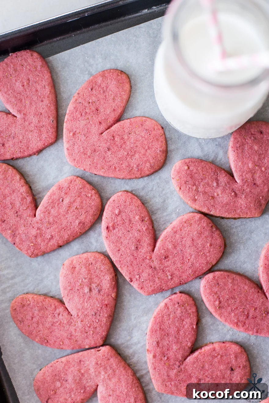 Strawberry Lemon Sugar Cookies Recipe with Fresh Fruit Zest 3 Overhead photo of pink heart shaped cookies on a tray with a bottle of milk with two straws