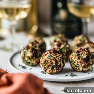Cranberry Orange Cheesecake Bites: Festive Party Appetizer 12 Cranberry orange cheese balls on a white plate next to an orange linen and champagne with a beige background.