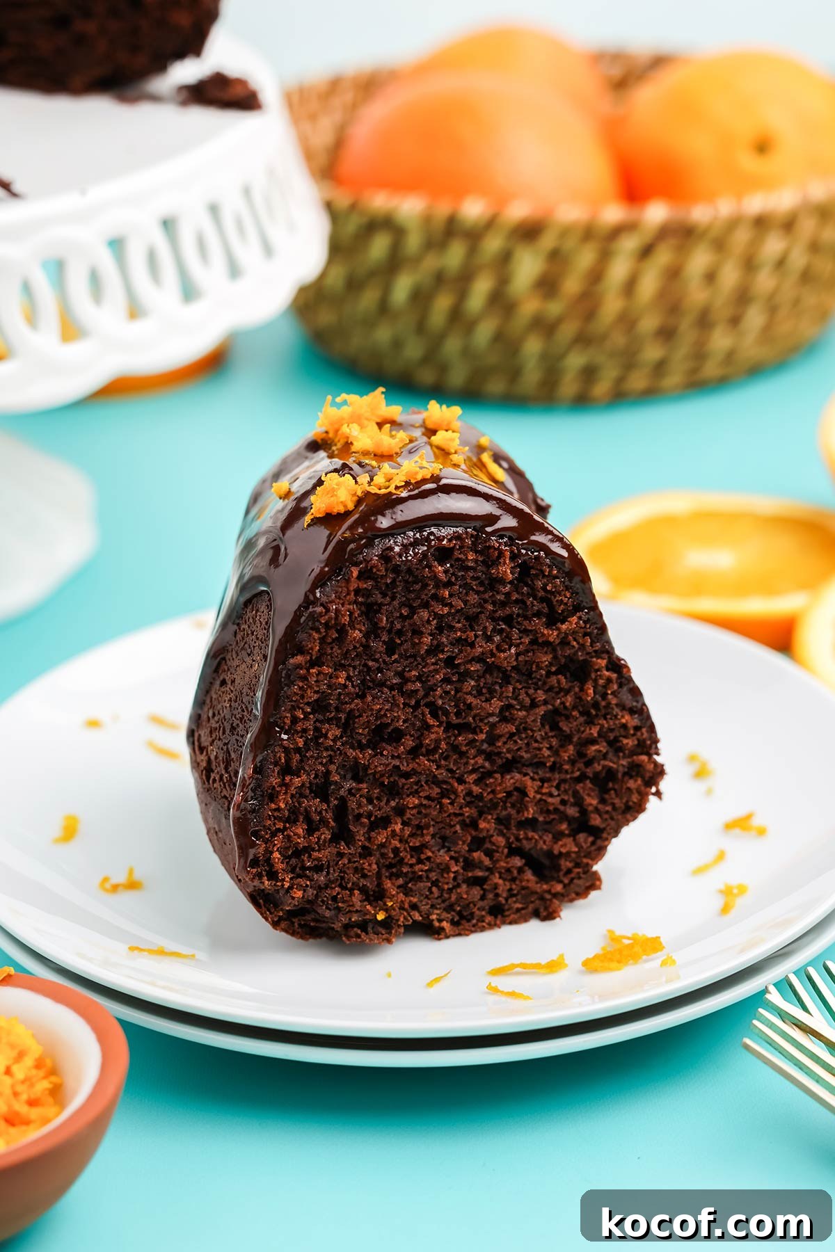 Slice of chocolate and orange cake with ganache on a plate.