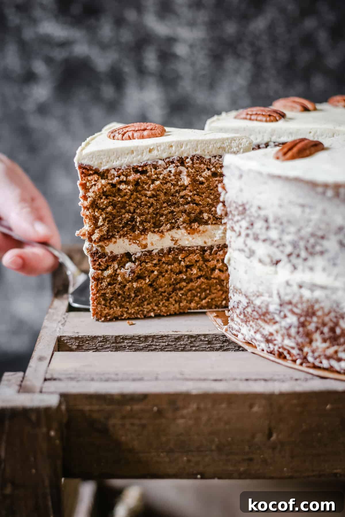 Gluten-Free Coffee Pecan Cake Recipe for Moist, Flavorful Slices 4 Hand pulling out a slice of Pecan Butterscotch Latte from whole cake on a wooden box