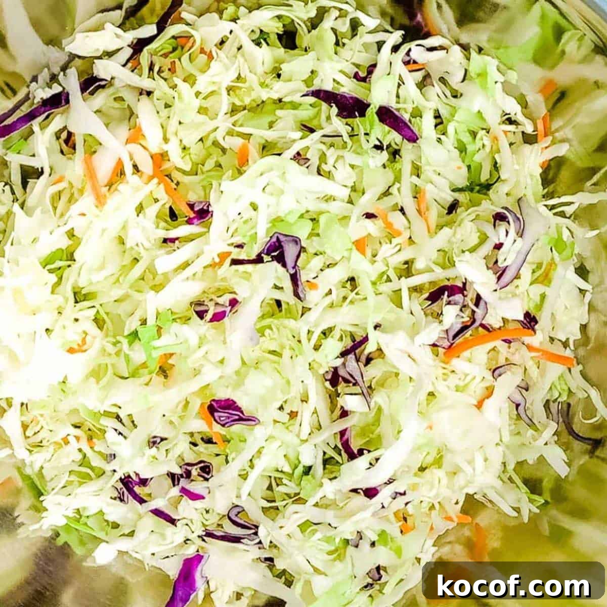Shredded cabbage and carrots added to a large mixing bowl.