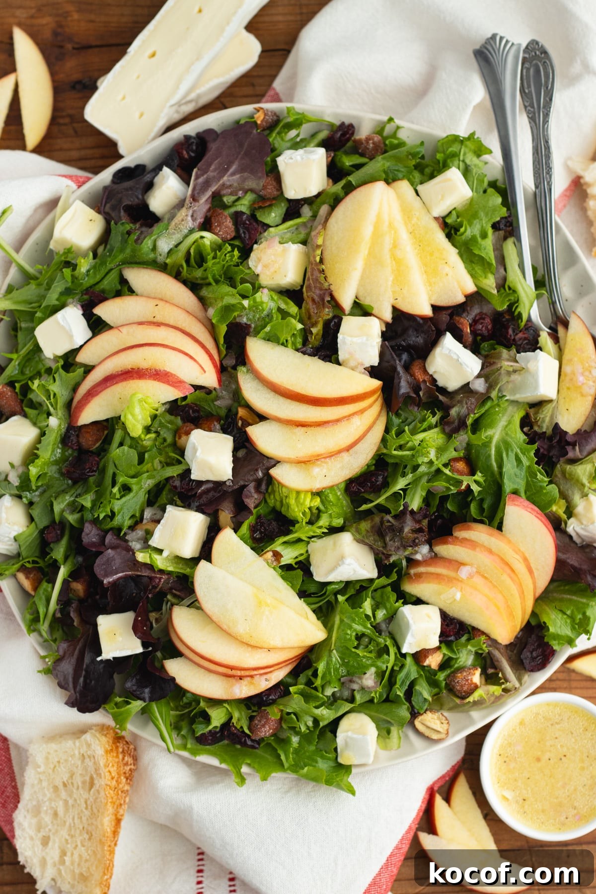 This is a picture of a plate filled with the salad with brie, apple, cranberries and almonds.