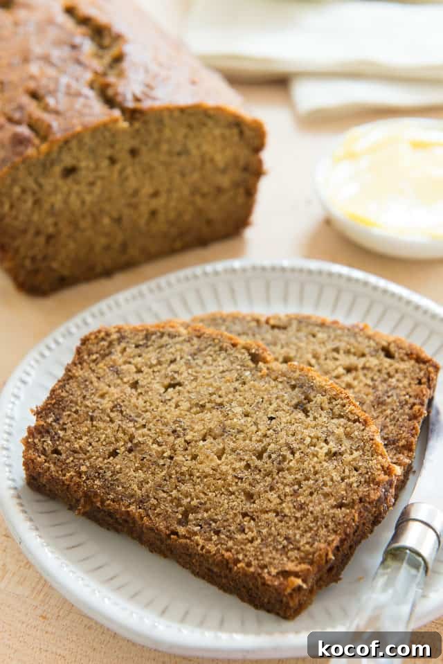 Banana Bread Slices on a White Plate with Remaining Loaf on Wooden board