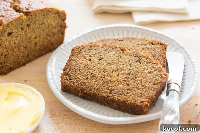 Banana Bread Sliced and Plated on White Dish with Remaining Loaf on Board