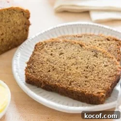 Banana Bread Slices on a White Plate with Remaining Loaf on Wooden board