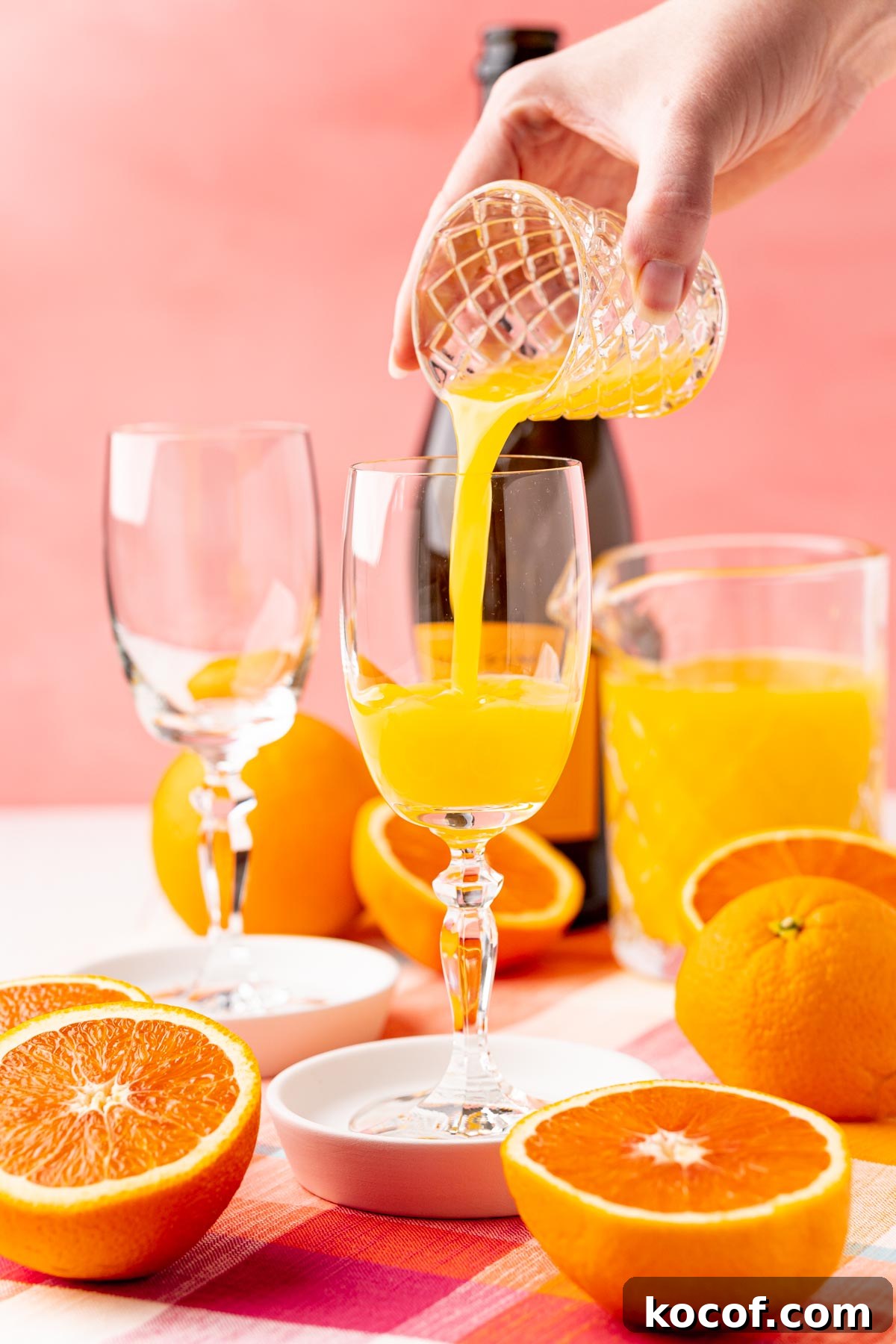Orange juice being poured into a champagne flute to make a mimosa.