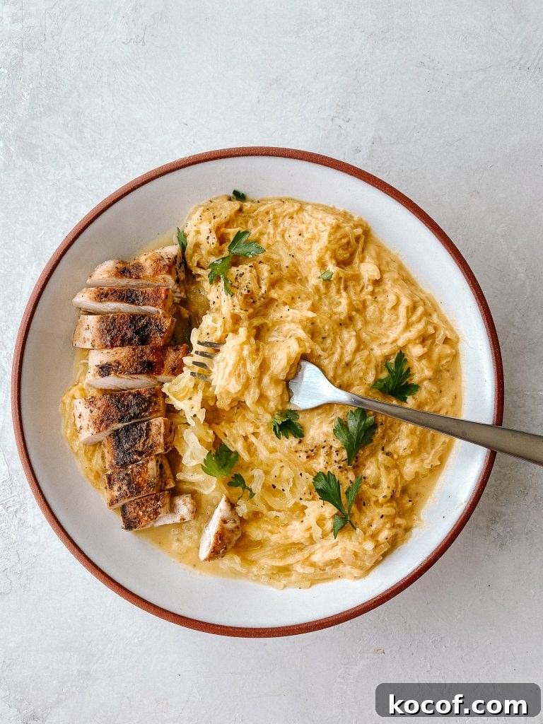 spaghetti squash with butternut mac and cheese sauce with sliced chicken breast and a fork