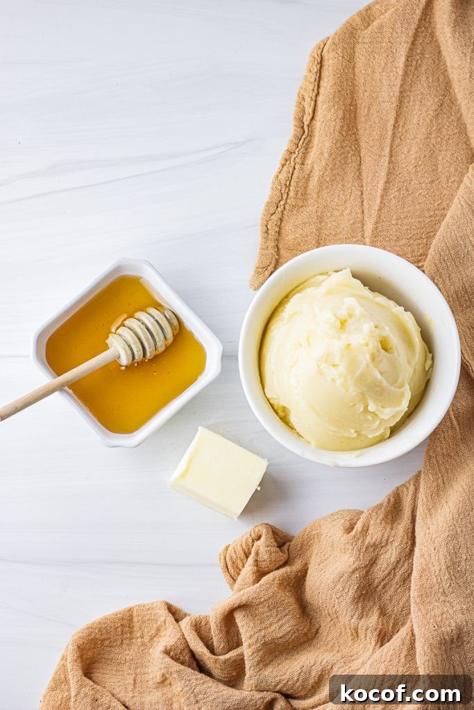 white bowl with honey butter and honey and block of butter next to it