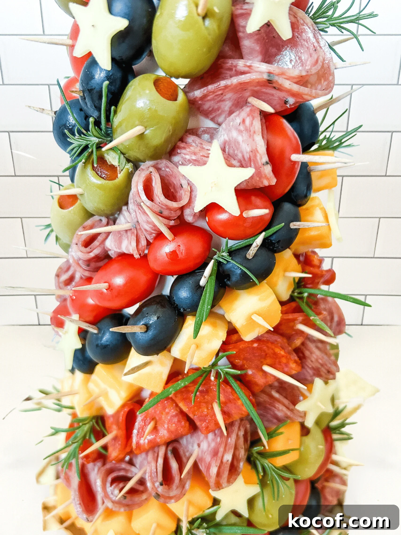 Close up of a charcuterie tree with meats, cheeses, olives, and stars stuck into a styrofoam cone with toothpicks.