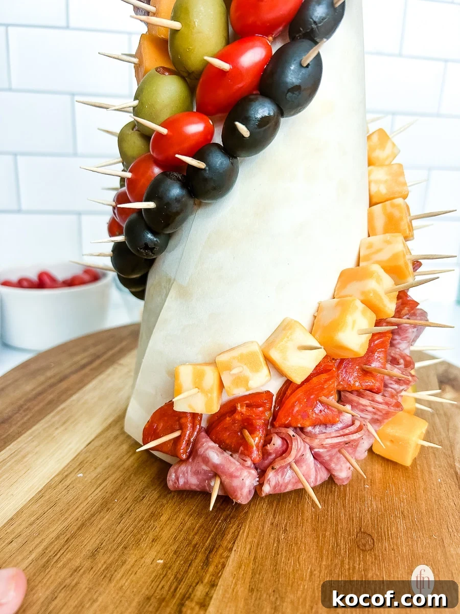 Meats and cheeses pinned to a foam cone with toothpicks.