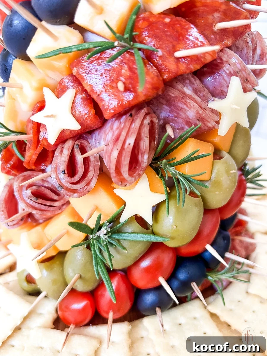 Close up of a charcuterie tree with meats, cheeses, olives, and stars stuck into a styrofoam cone with toothpicks.