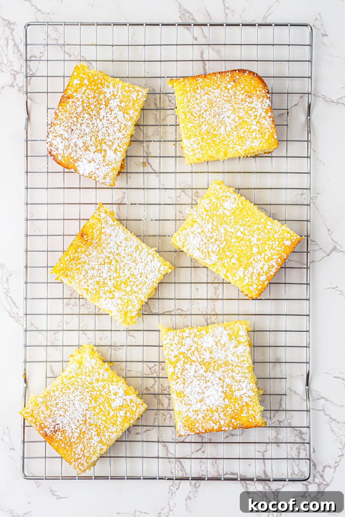 Bright yellow lemon bars baked and cooling on a wire rack. 