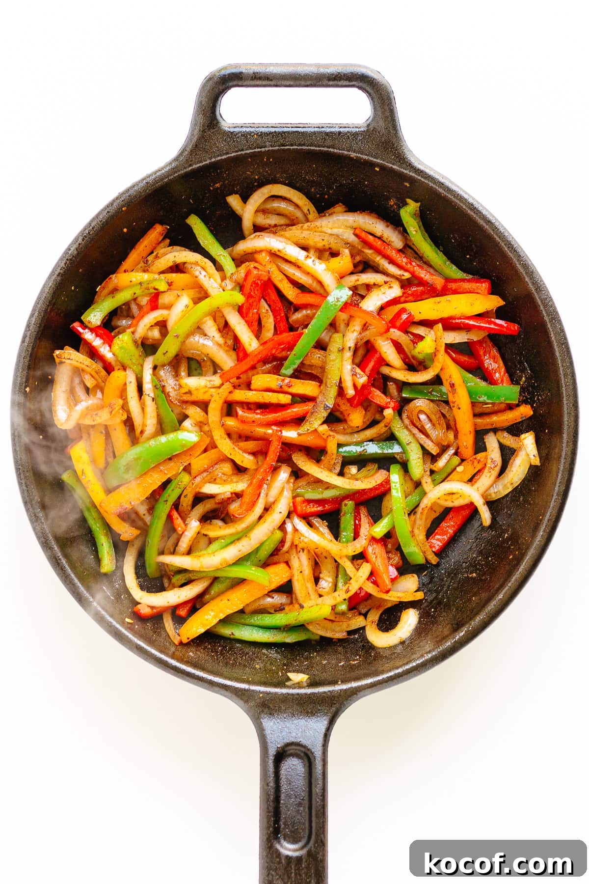 Quick Skillet Ground Beef Fajitas with Peppers and Onions 6 Fajita veggies in a cast iron skillet on a white background.