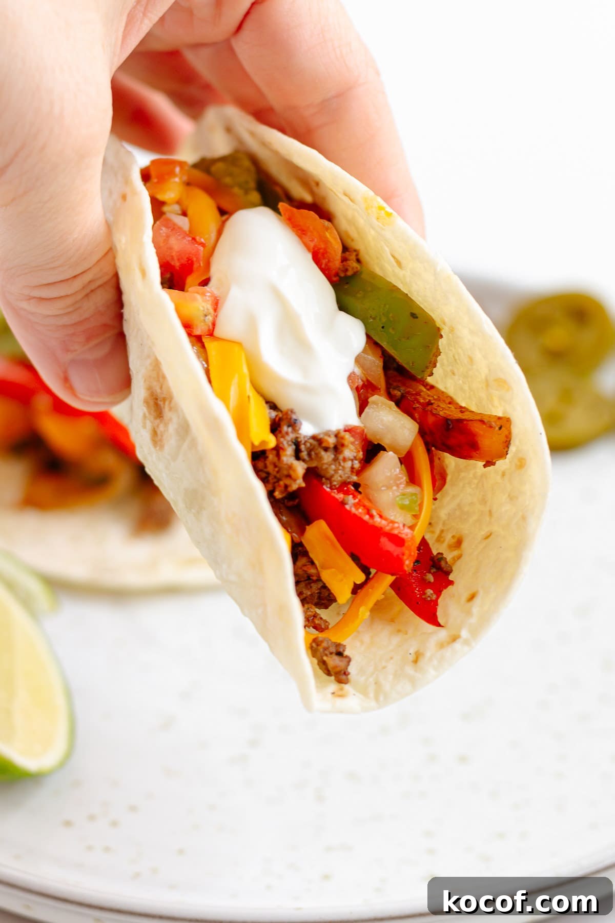 Quick Skillet Ground Beef Fajitas with Peppers and Onions 10 Hand holding a ground beef fajita on a flour tortilla.
