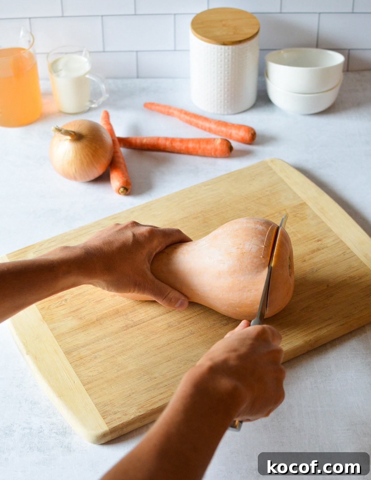 hand cutting the end off a butternut squash. 