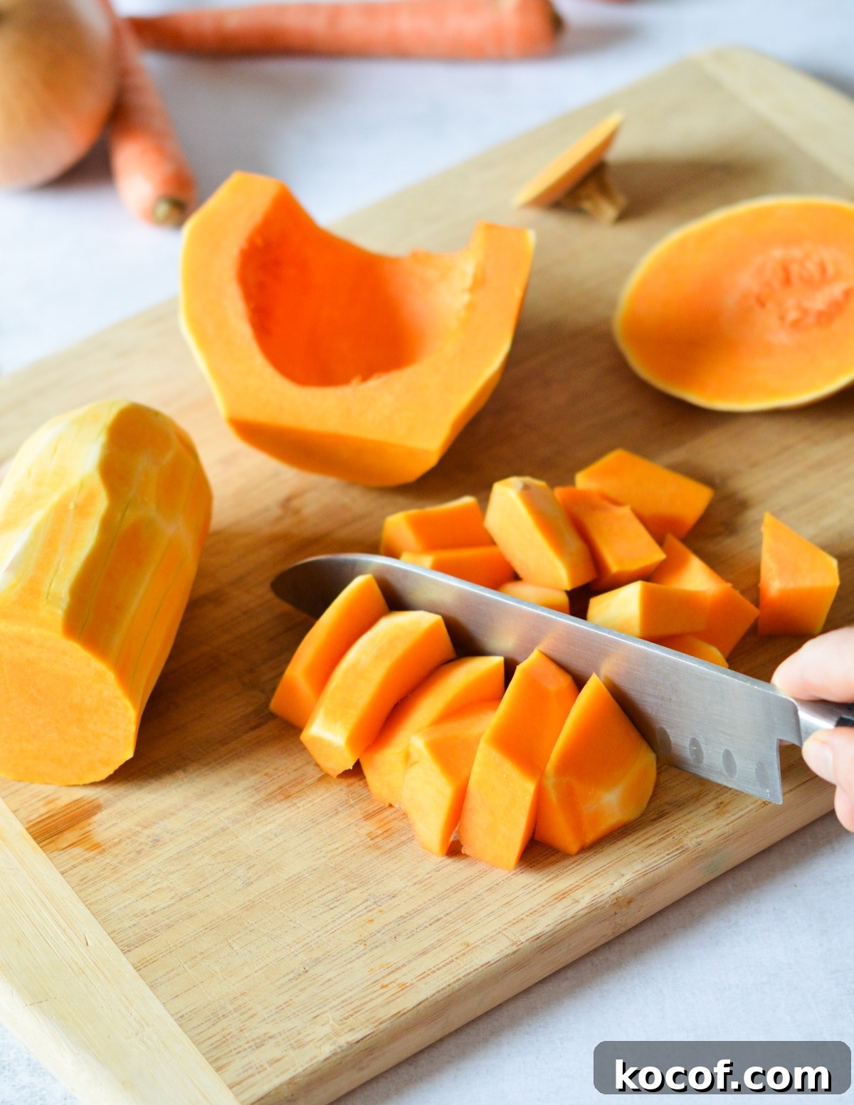 knife cutting butternut squash strips into chunks. 