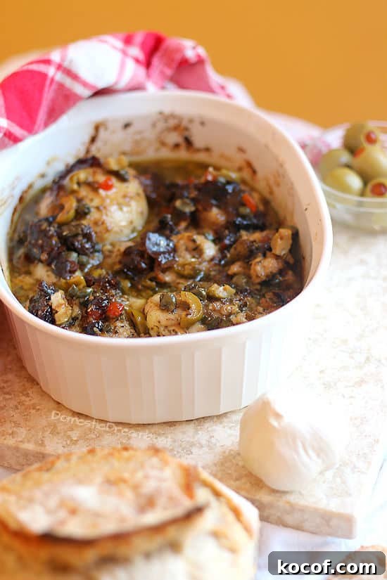Chicken Marbella with Prunes, Olives, and Capers in a white casserole dish.
