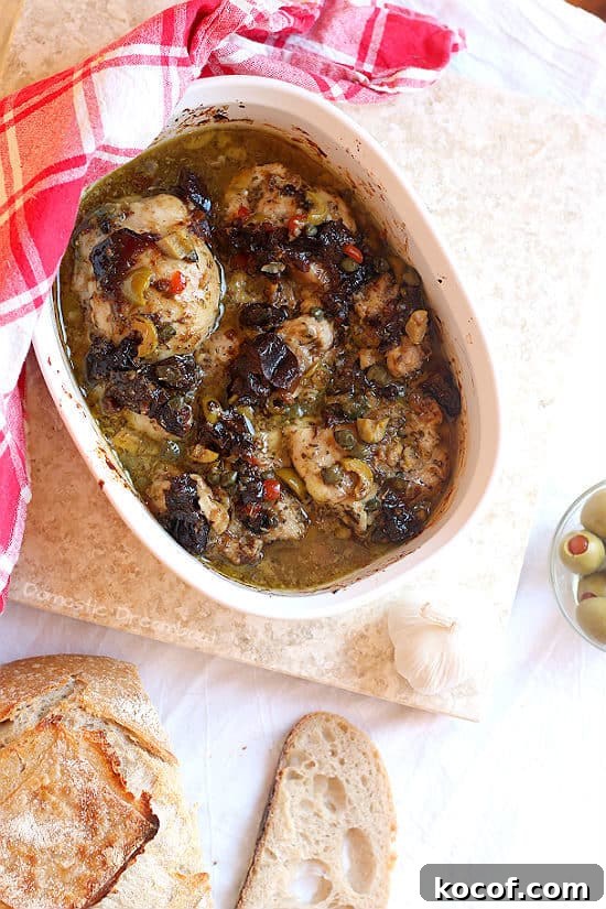 Overhead photo of Chicken Marbella with Prunes, Olives, and Capers in a white casserole dish.