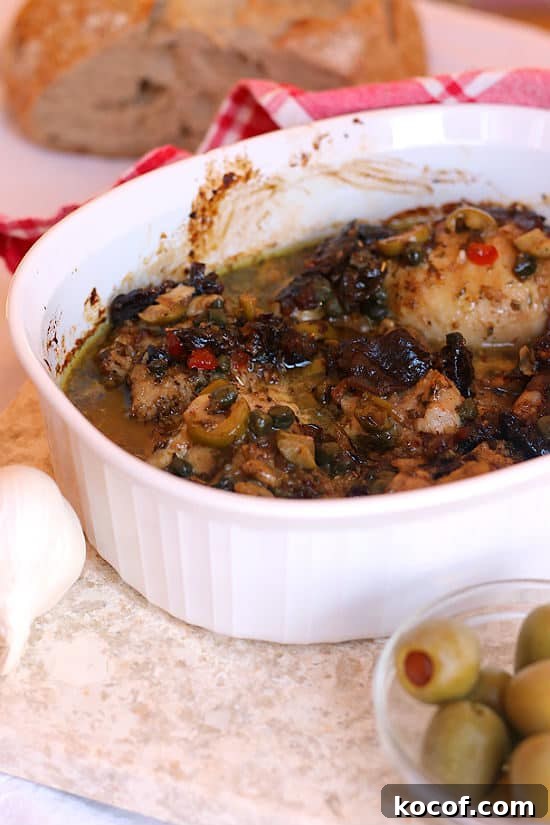 Chicken Marbella with Prunes, Olives, and Capers in a white casserole dish.