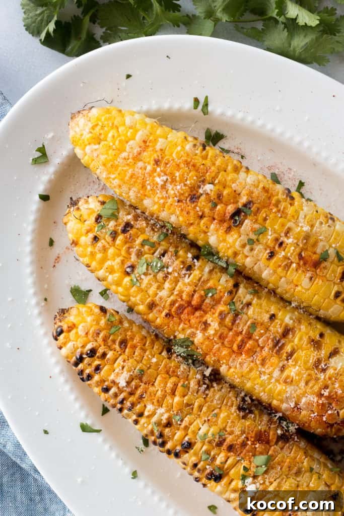 top down shot of grilled corn on the cob with toppings on a white platter