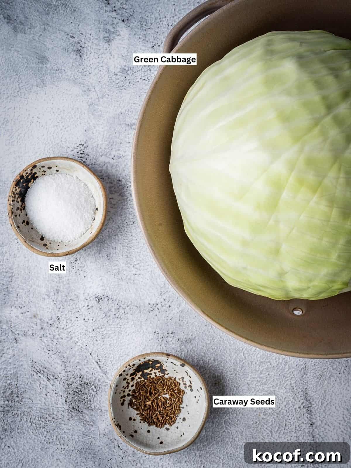 The recipe ingredients on a table (cabbage, salt, caraway seeds).