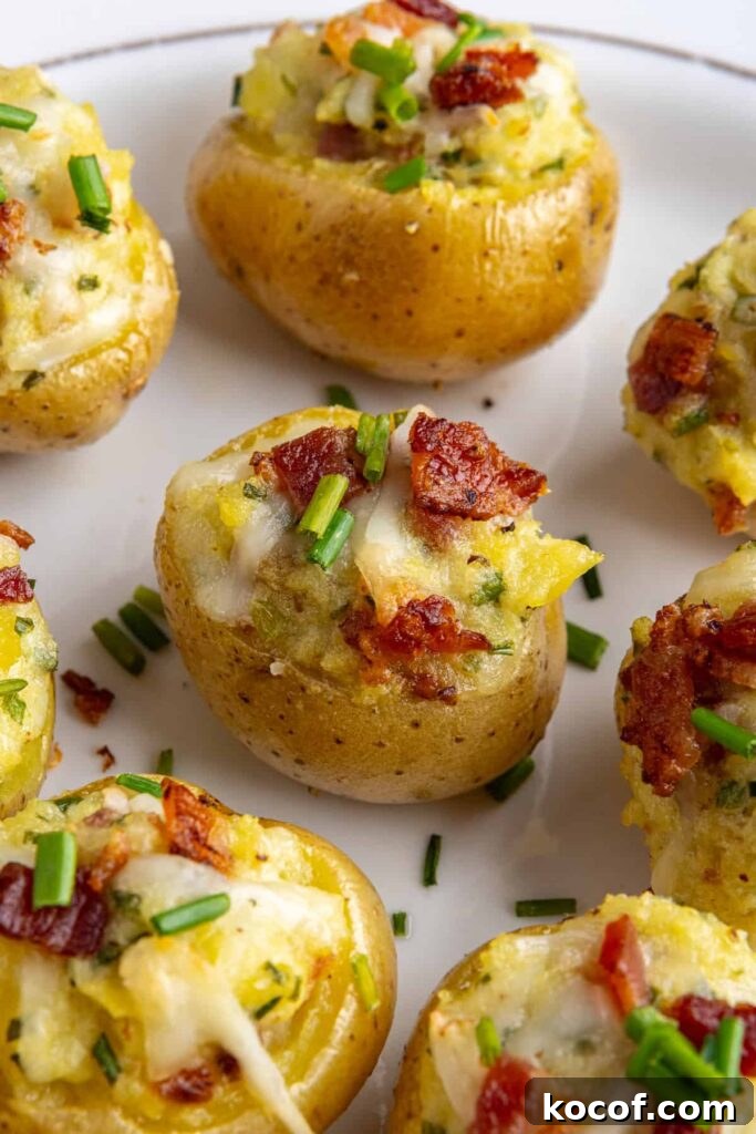 Angled view of creamy twice baked potatoes topped with bacon and chives on a serving plate