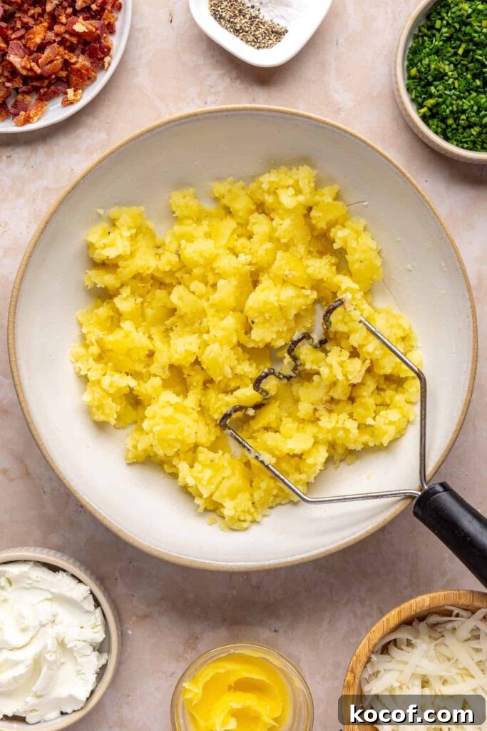Mashed potato flesh in a bowl, before adding goat cheese, ghee, bacon, and chives