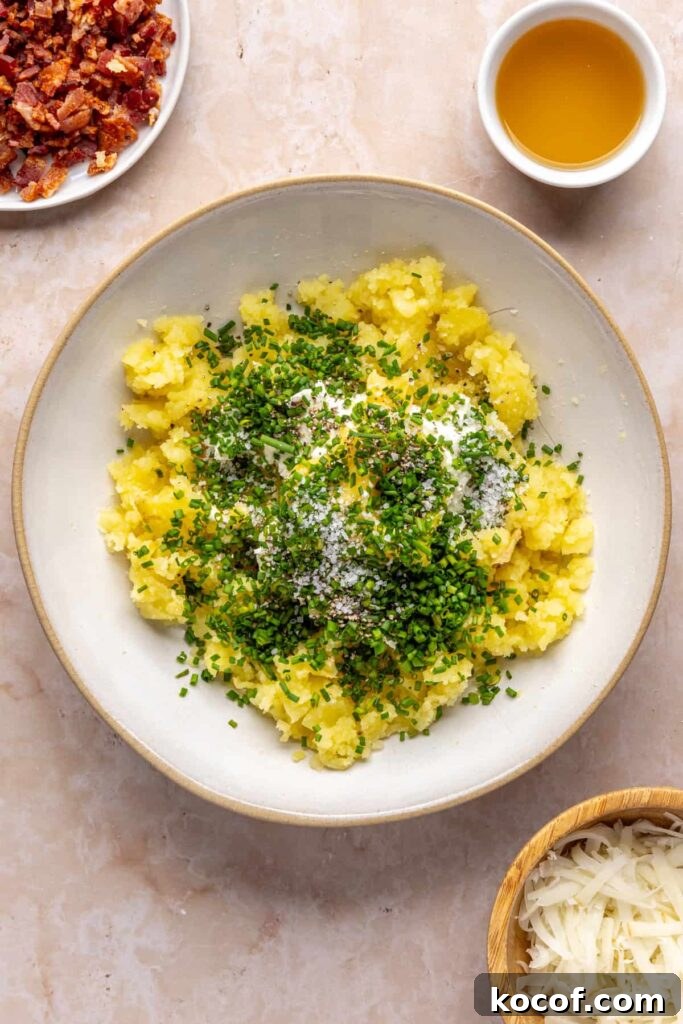 Mashed potato flesh in a bowl with goat cheese, ghee, and chives