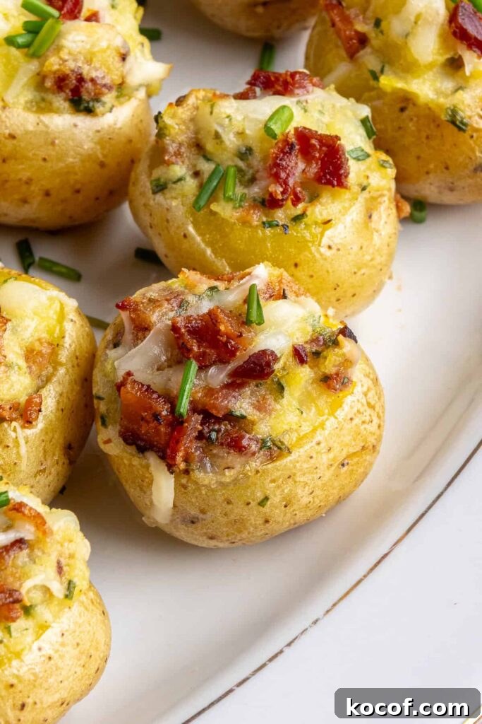 Angled view of creamy twice baked potatoes topped with bacon and chives on a serving plate
