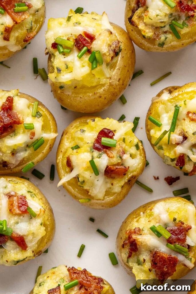 Close-up overhead of golden brown twice baked potatoes with cheesy filling, chives, and crispy bacon