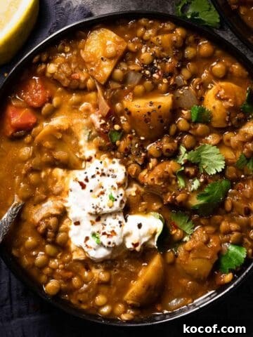 lentil potato soup in bowl with spoon in bowl and lemon wedge on the side