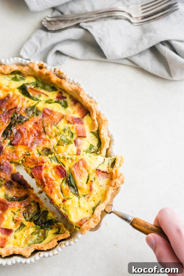 Perfect Breakfast Quiche A hand lifting a slice of quiche out of the pan.