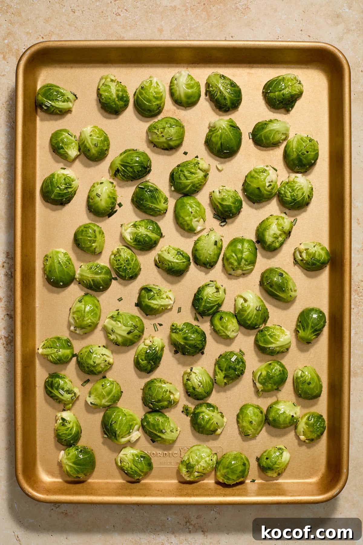 Brussels sprouts arranged cut side down on a large sheet pan.