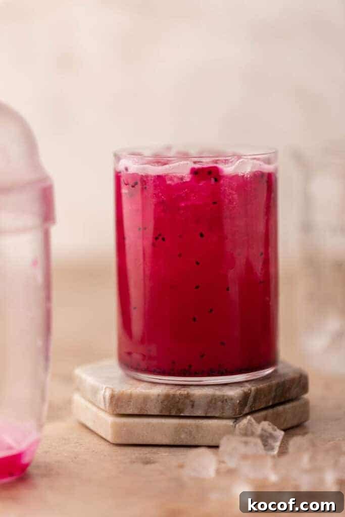 Starbucks mango dragonfruit refresher with dragonfruit pieces in a clear glass