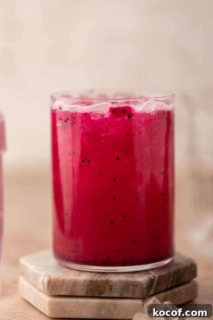 Iced Starbucks dragonfruit refresher pink drink with dragonfruit pieces on a coaster