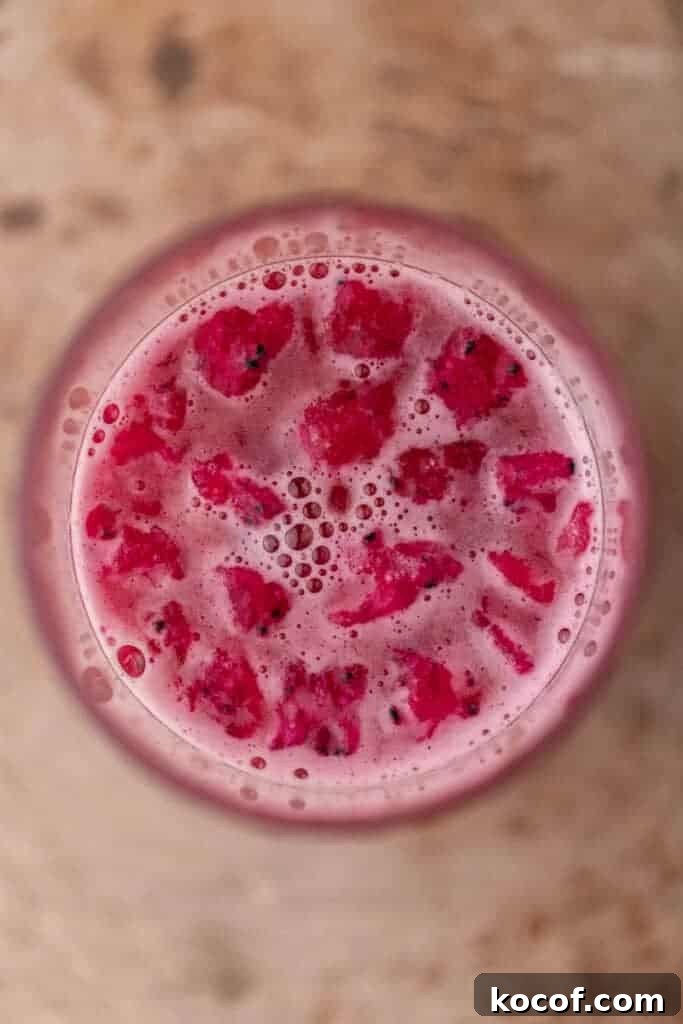 Top view of a pink iced drink with dragonfruit pieces