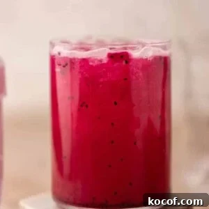 Iced Starbucks dragonfruit refresher pink drink with dragonfruit pieces on a coaster