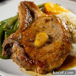 bone in pork chop on a white plate with green beans and white rice