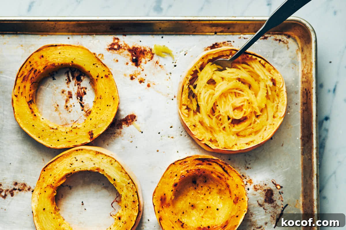 Spaghetti squash cut into rings cooked on a metal baking sheet with noodles scooped out