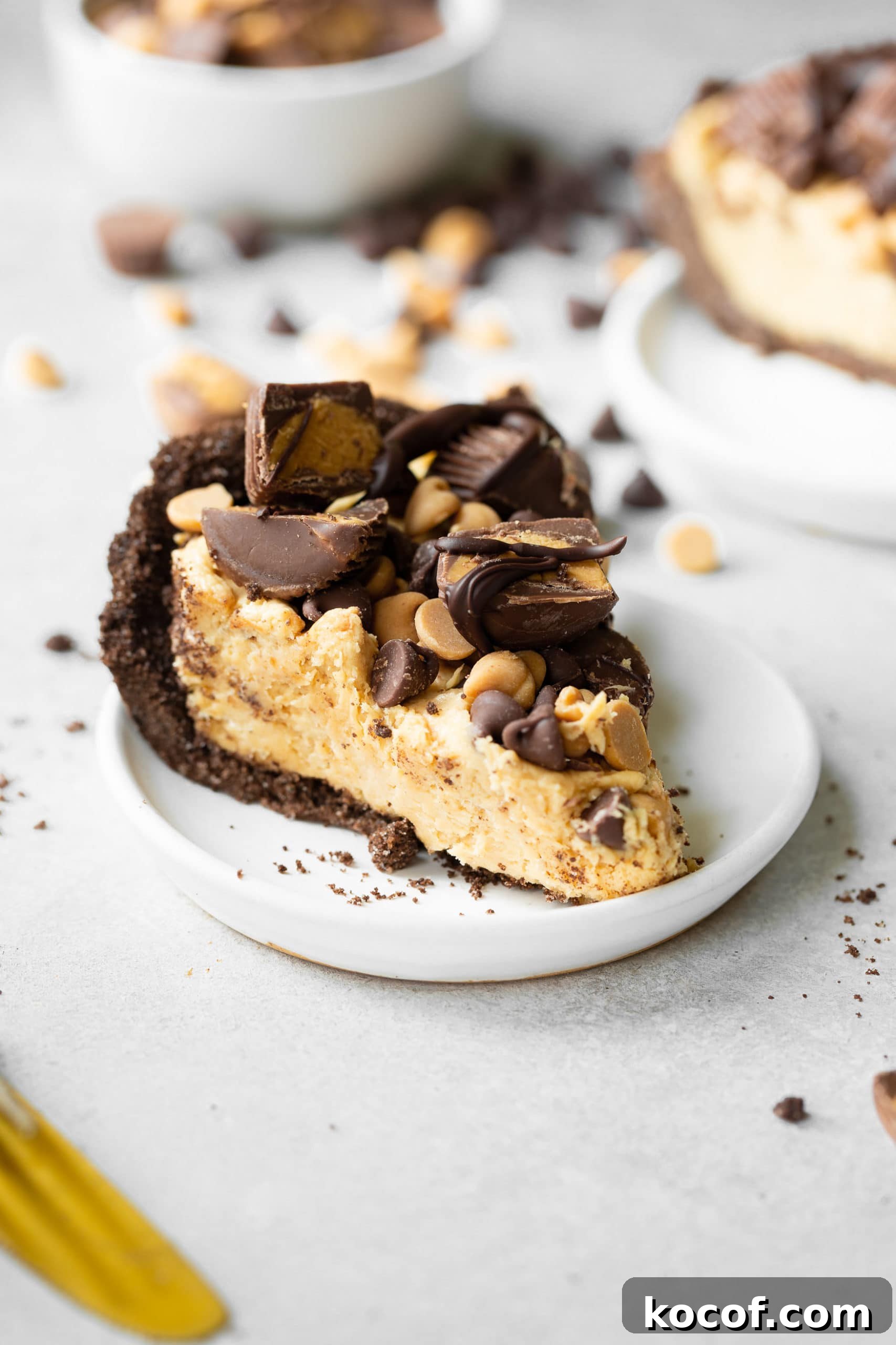 A slice of peanut butter pie on a white plate with the pie topped with candy.