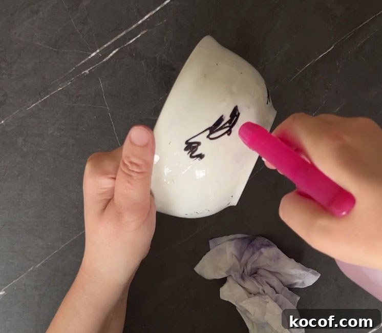 Create a Faux Marble Bowl: Step-by-Step DIY Tutorial 6 Hand spraying rubbing alcohol on white bowl with black scribbles on it