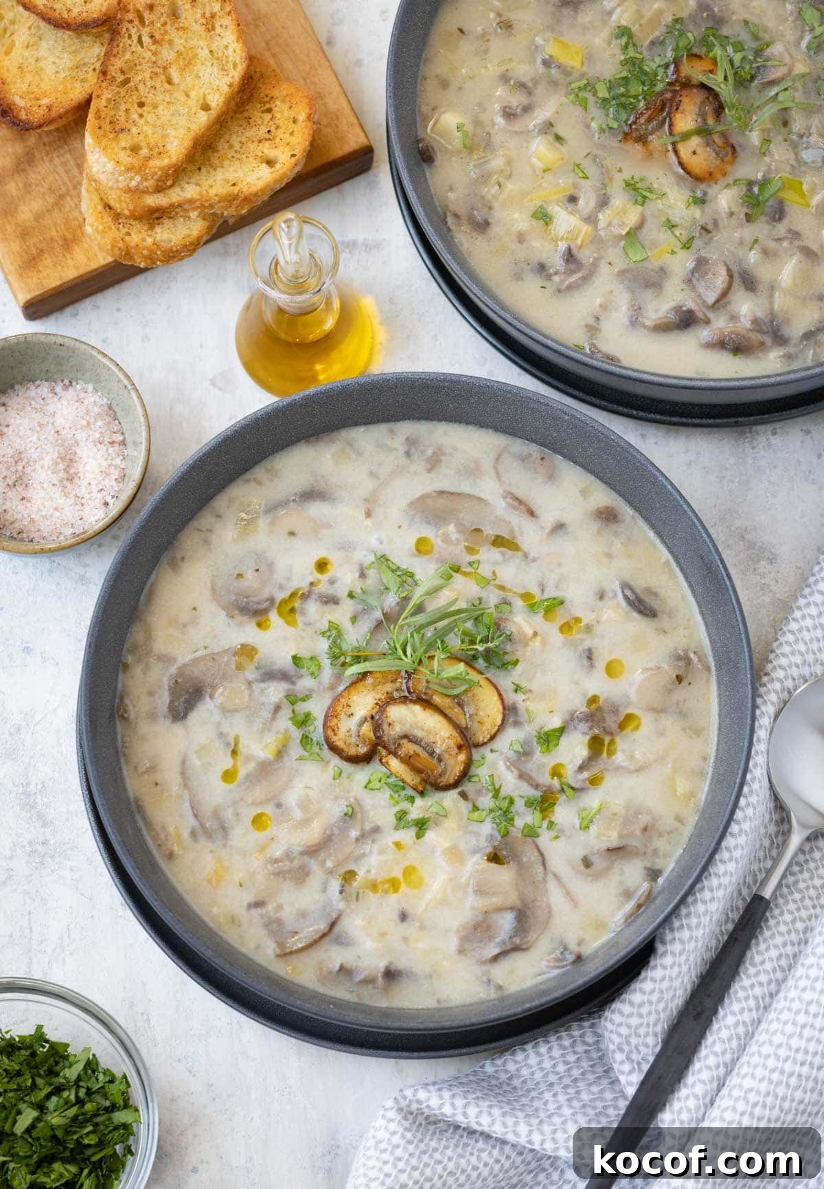 Gray bowls of leek and mushroom soup with garlic toast and parsley.