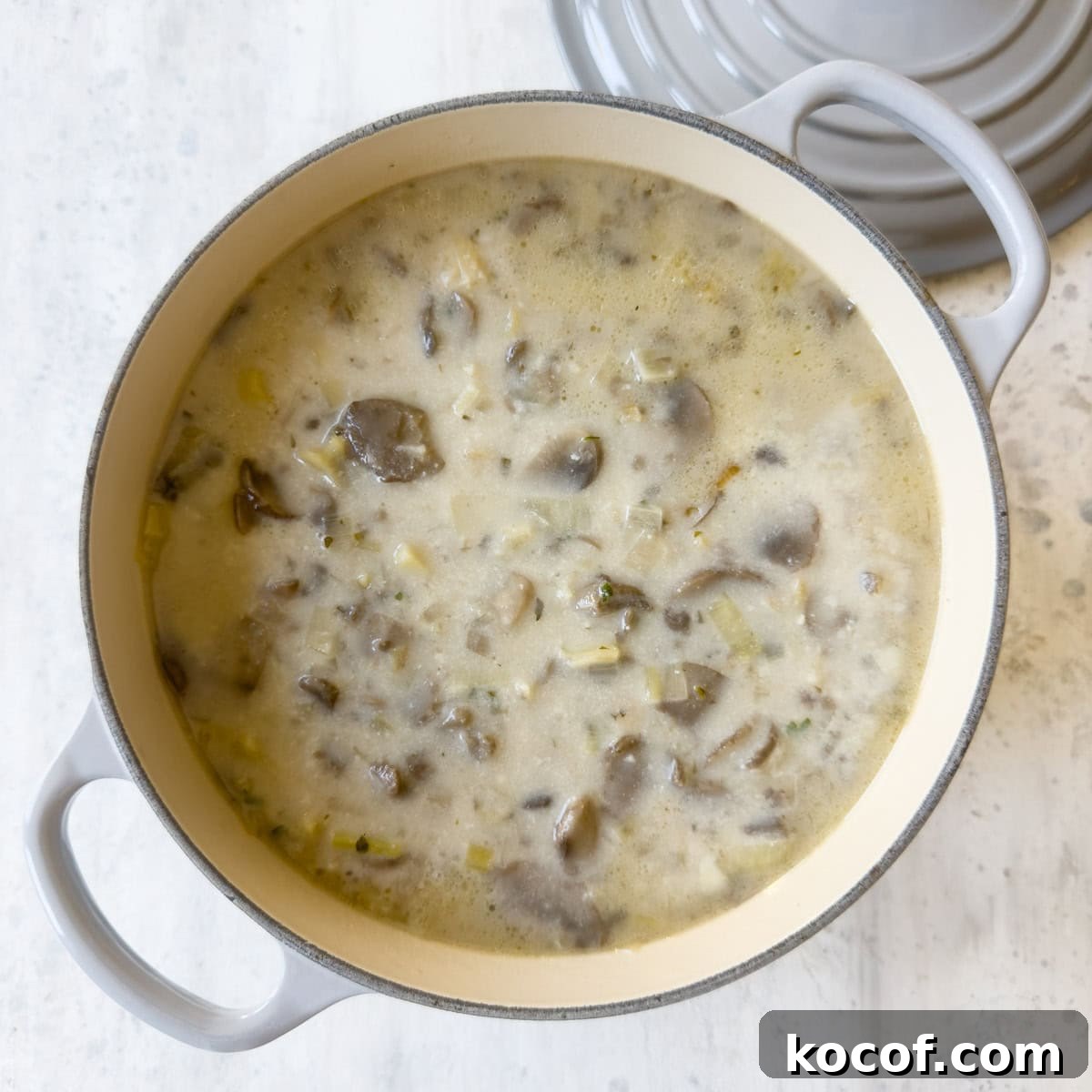 A gray dutch oven filled with finished leek and mushrooms soup ready to eat.