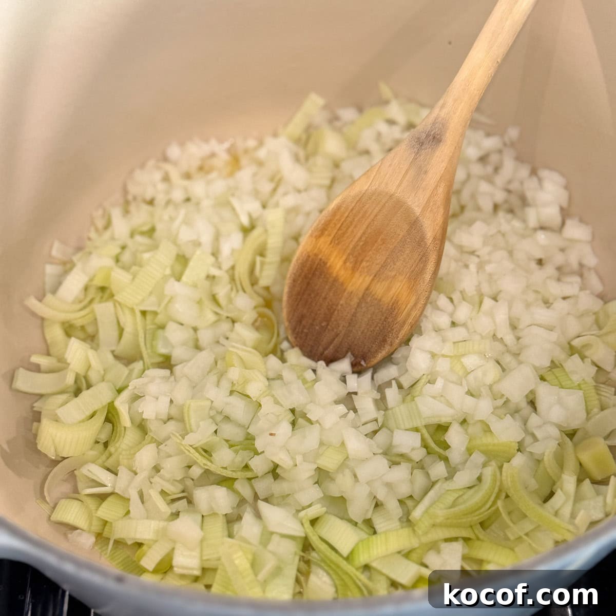 Chopped onions and leeks sautéing in a dutch oven.