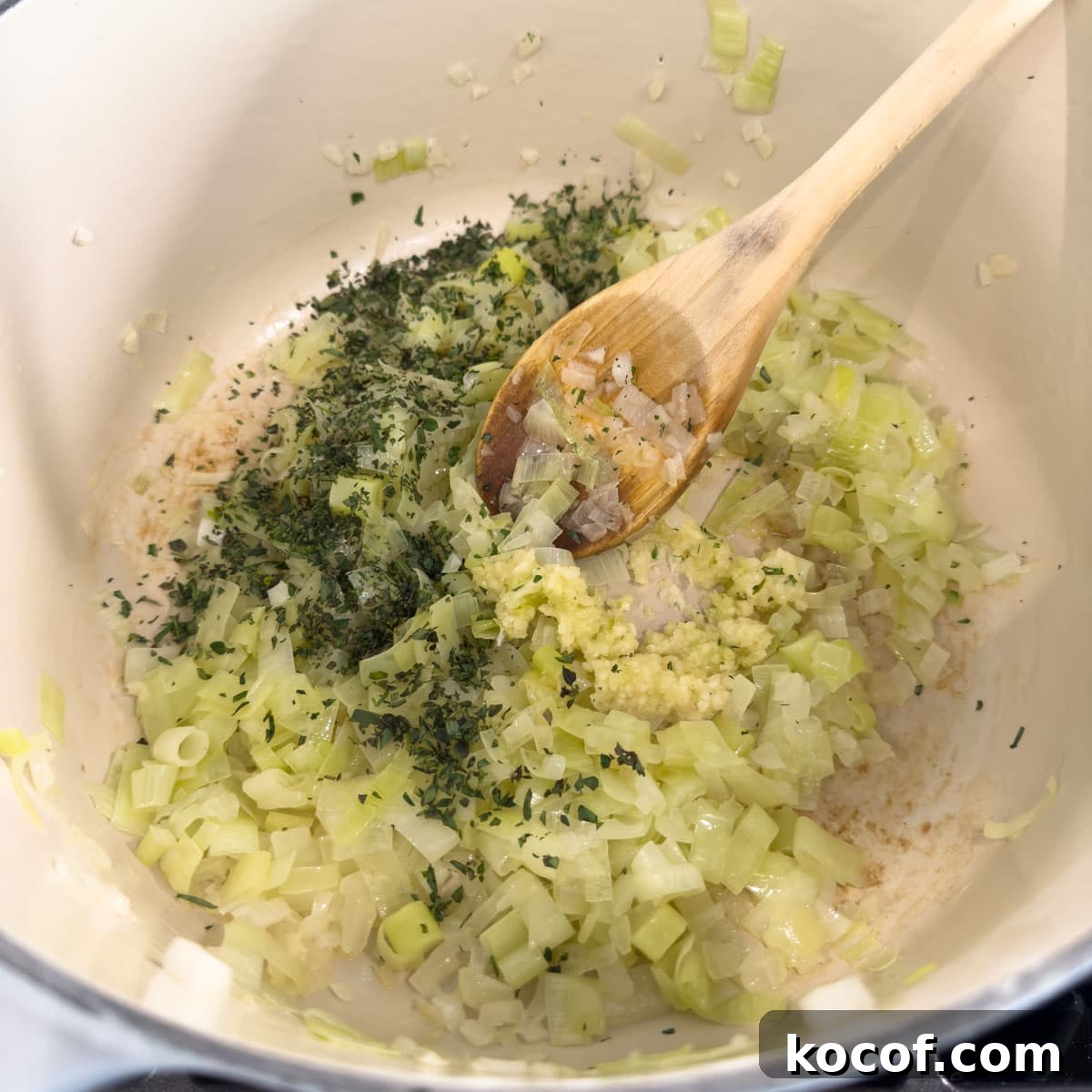 Cooked onions and leeks with green herbs making a soup base.