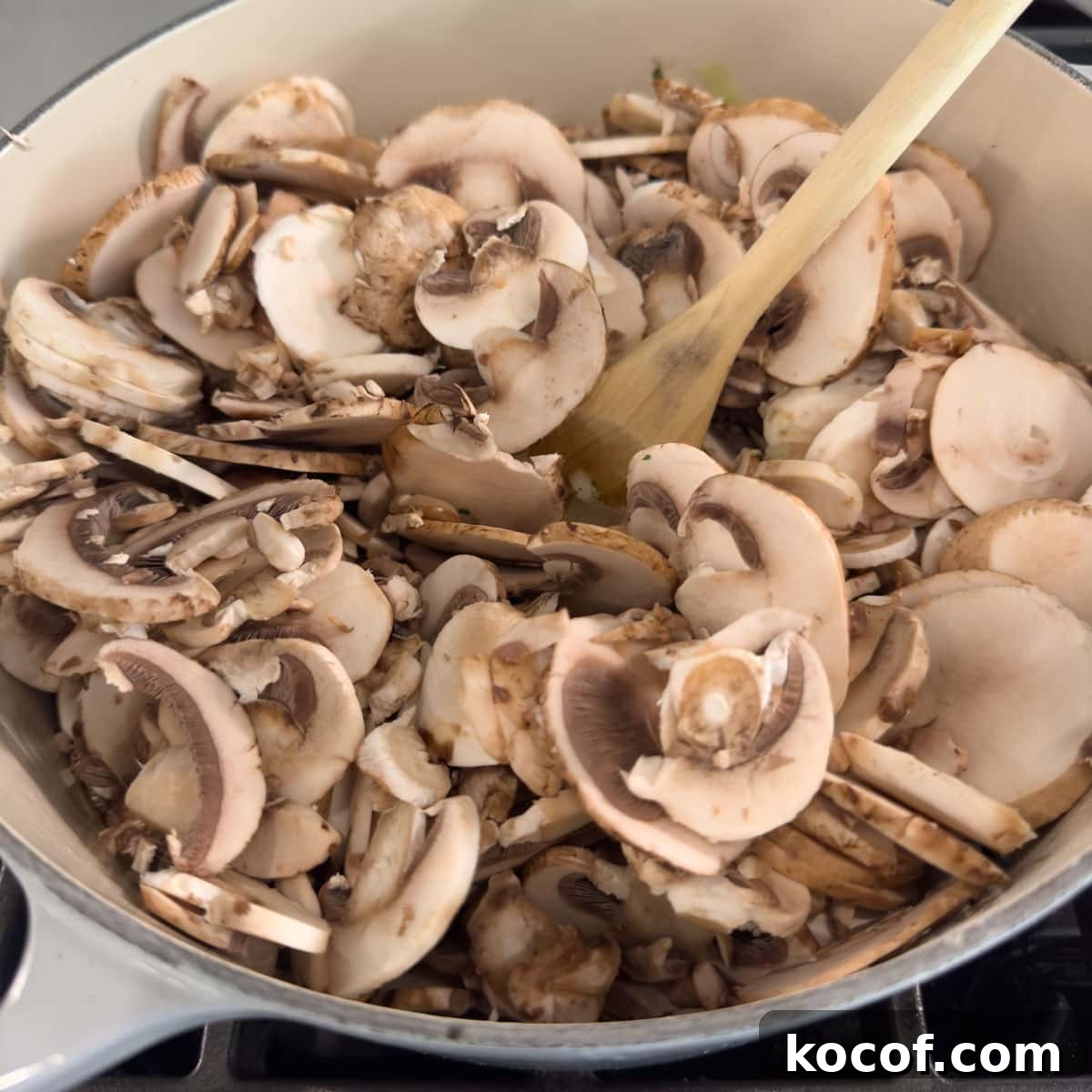 A pot full of raw sliced mushrooms cooking down for soup.