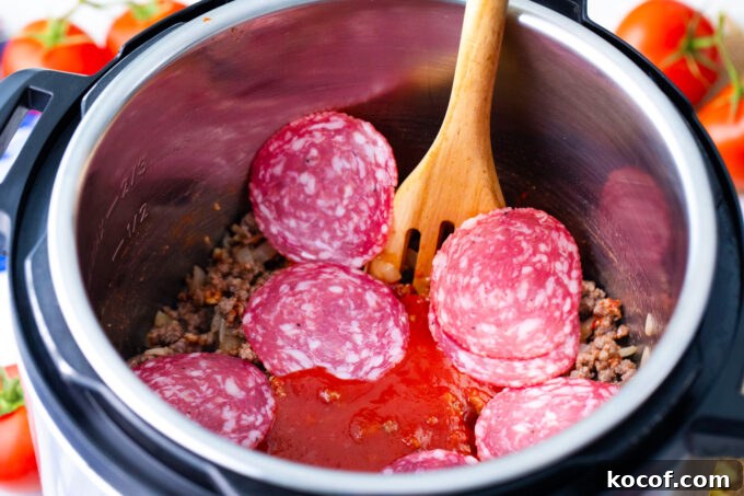 Adding tomato sauce and pepperoni to seared ground beef