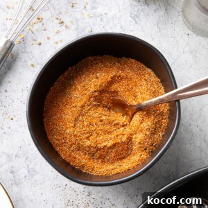 bowl of cajun seasoning with a spoon in it and spices on the table
