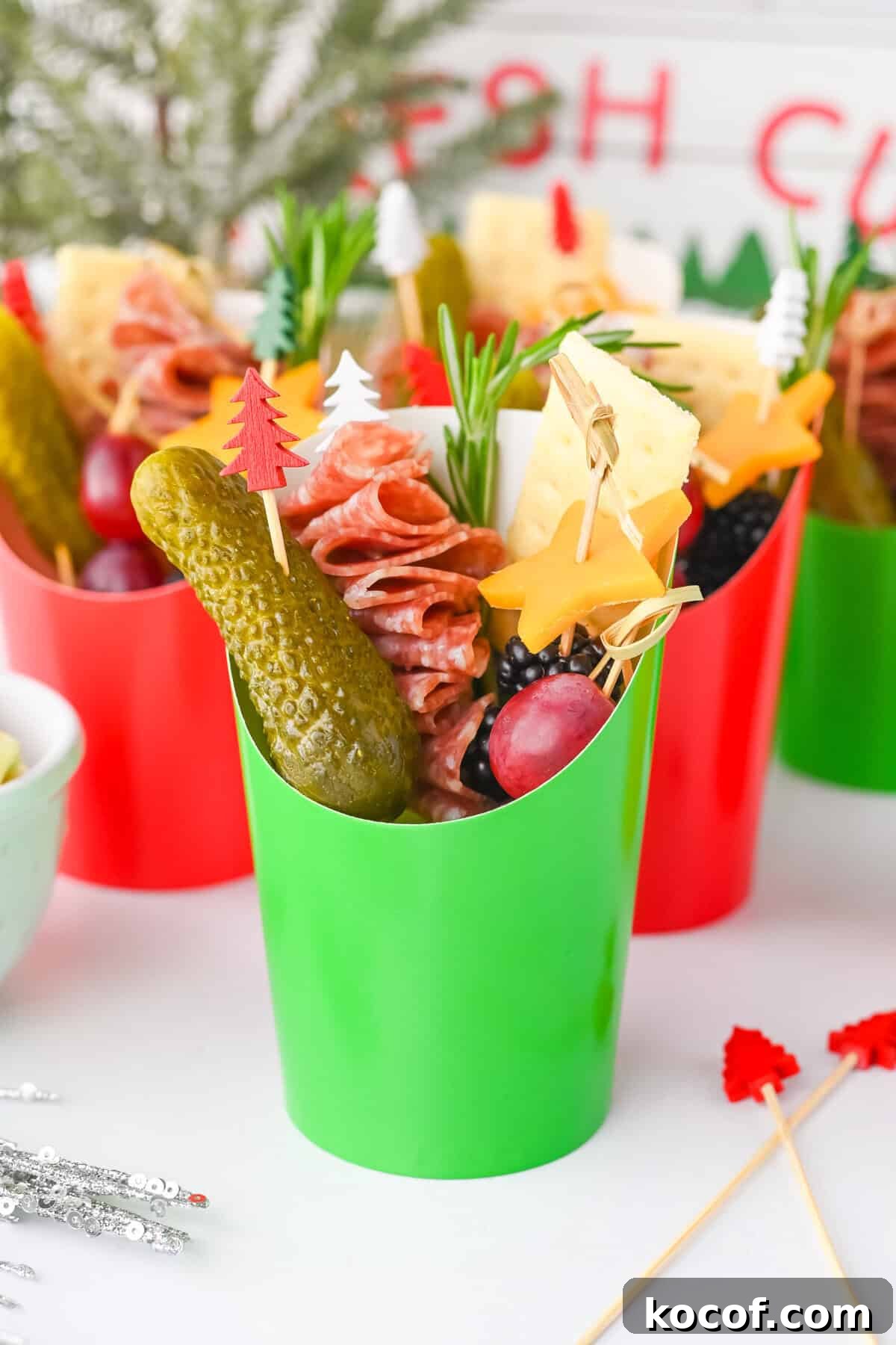 Green charcuterie cup with holiday picks and snacks.